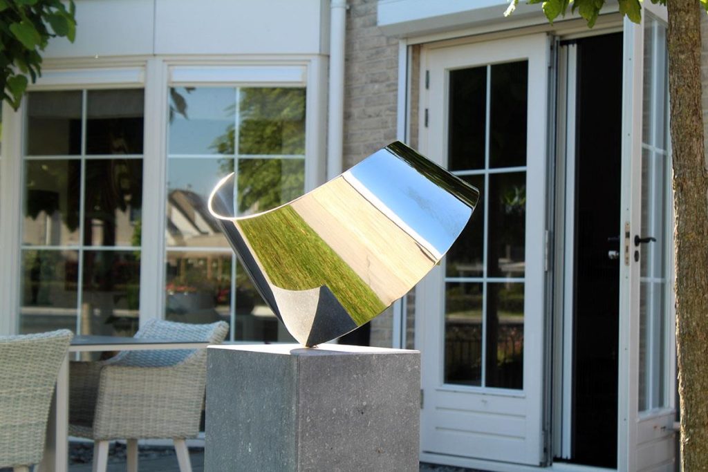 Moderne RVS sculptuur met glanzend oppervlak in tuin als decoratief kunstwerk